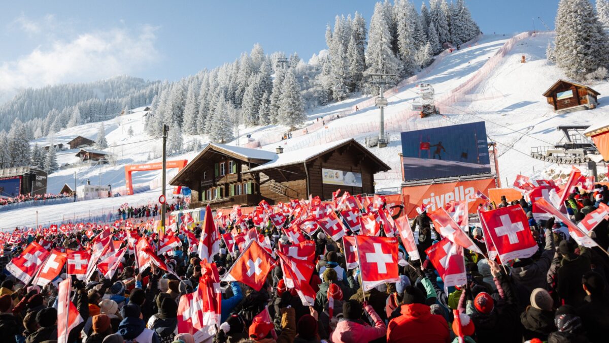 Viele Zuschauer schauen einem Skirennen zu und halten dabei eine Schweizerfahne