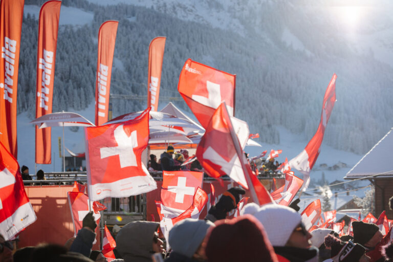 Schweizer Fahnen und Rivella Banner bei Wintersportveranstaltung.
