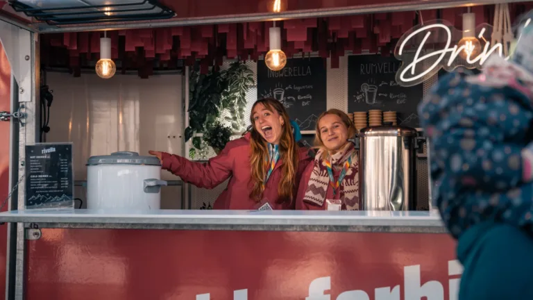 Rivella Verkaufsstand mit zwei lächelnden Personen im Winter.