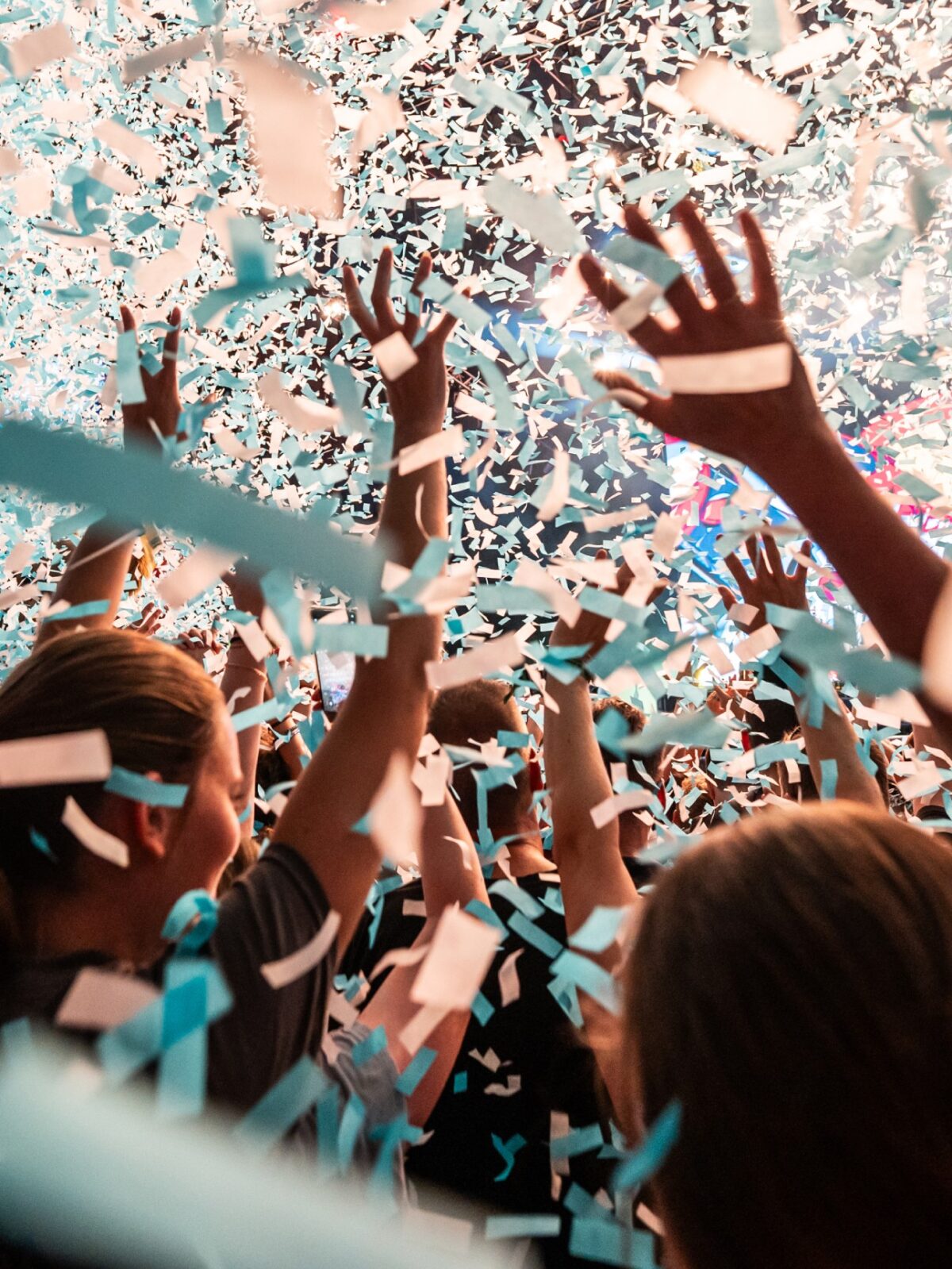 Menschen feiern umgeben von blau-weißem Konfetti bei einem Event.