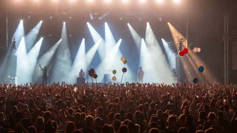 Konzert mit Publikum, bunten Luftballons und dynamischem Bühnenlicht.
