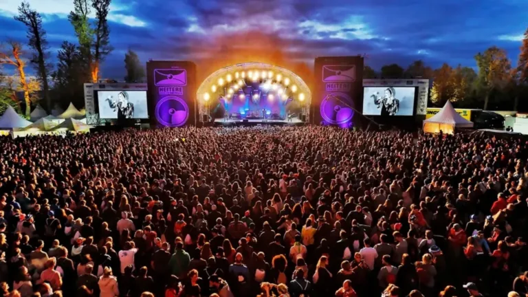 Ein großes Musikfestival mit Menschenmenge und beleuchteter Bühne.