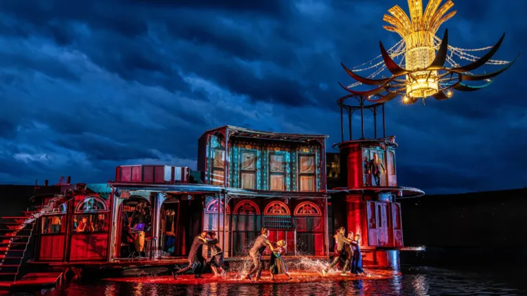 Eine bunte Bühne mit Aufführung auf dem Wasser bei Nacht.