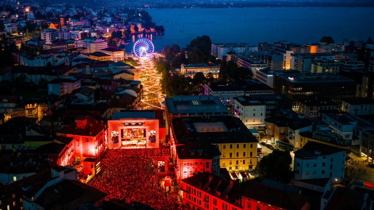 Blick auf belebtes Stadtfestival bei Nacht mit bunten Lichtern.