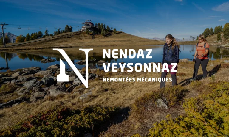 Zwei Menschen wandern in alpiner Landschaft bei sonnigem Wetter.