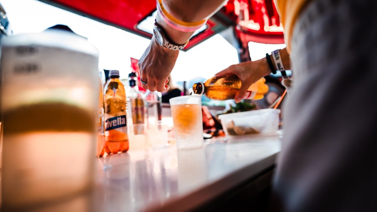 Person schenkt Rivella Rot in ein Glas im Freien ein.