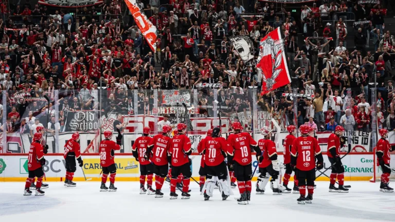 Eishockey-Spieler vor jubelnden Fans in einer Arena.